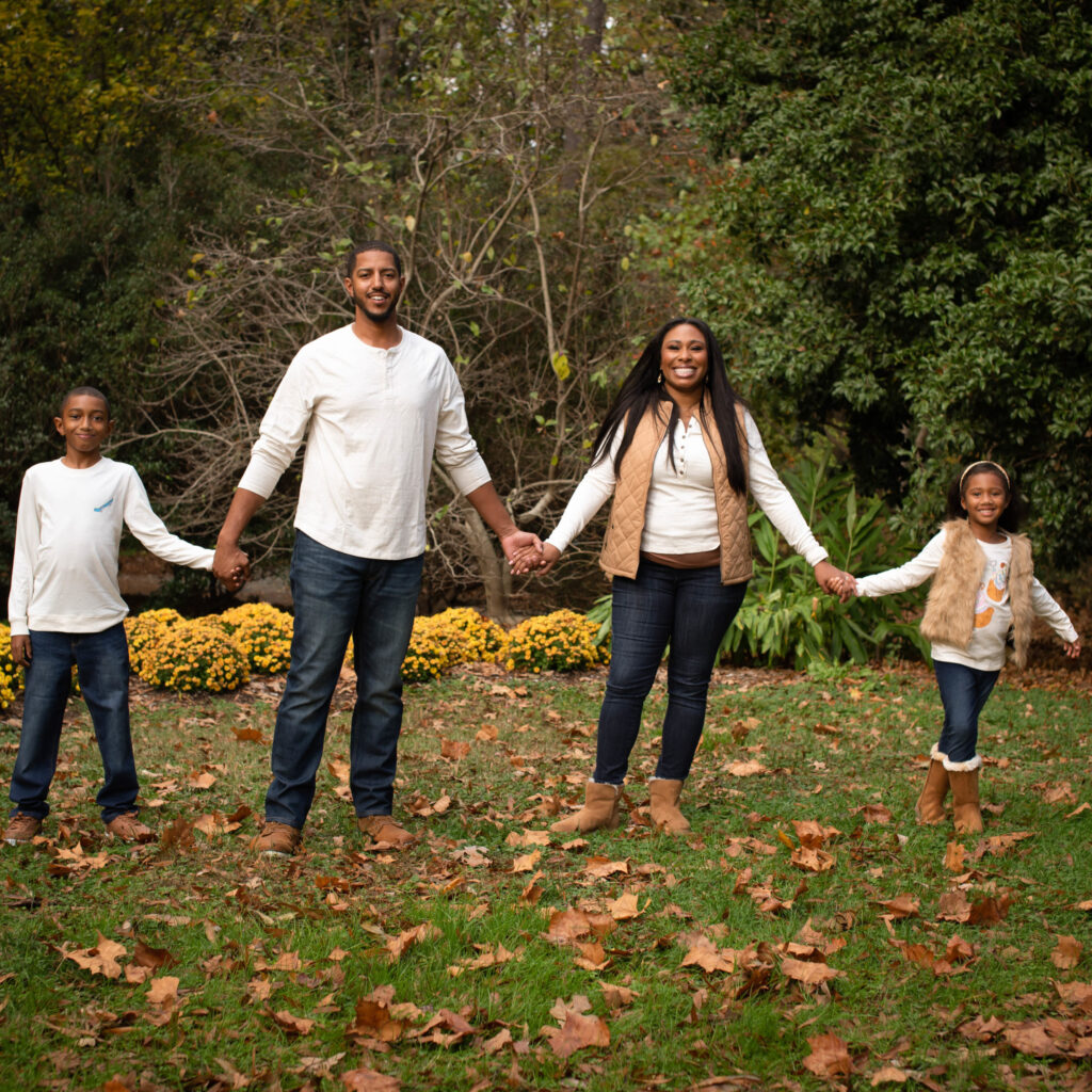 Young couple with their two children, holding hands in a fall scene